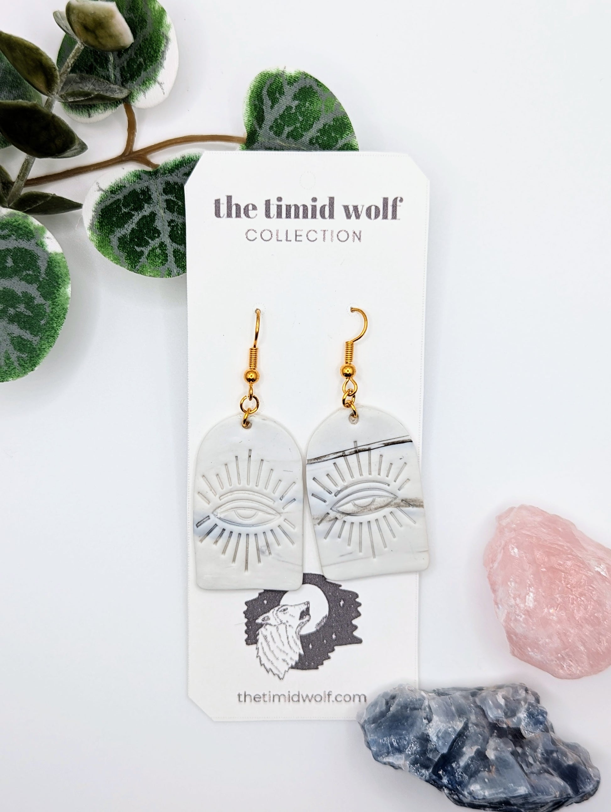 This photo shows a pair of earrings with an "All-Seeing Eye" design featured. The earring style is an arch with the design on it, dangling from stainless steel earring hooks.